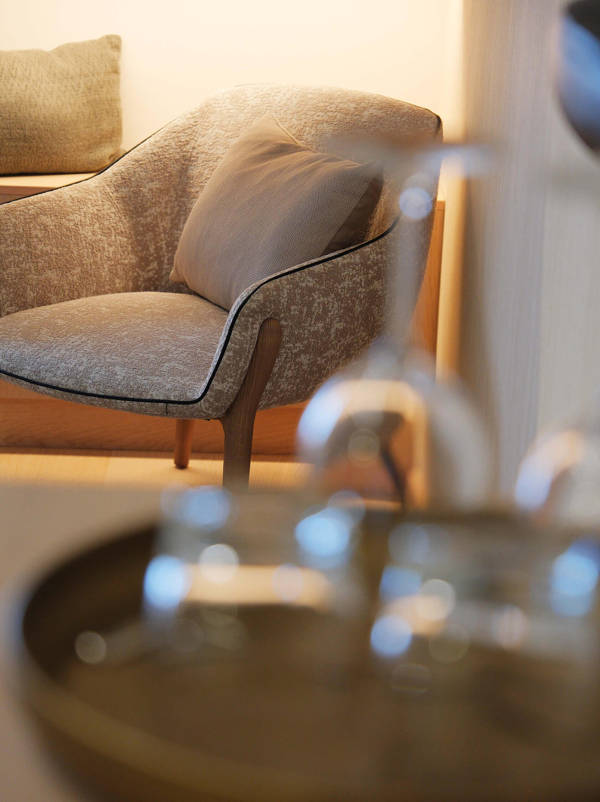 Sitzsessel mit Armlehnen, im Vordergrund unscharf ein Tisch mit Wassergläsern