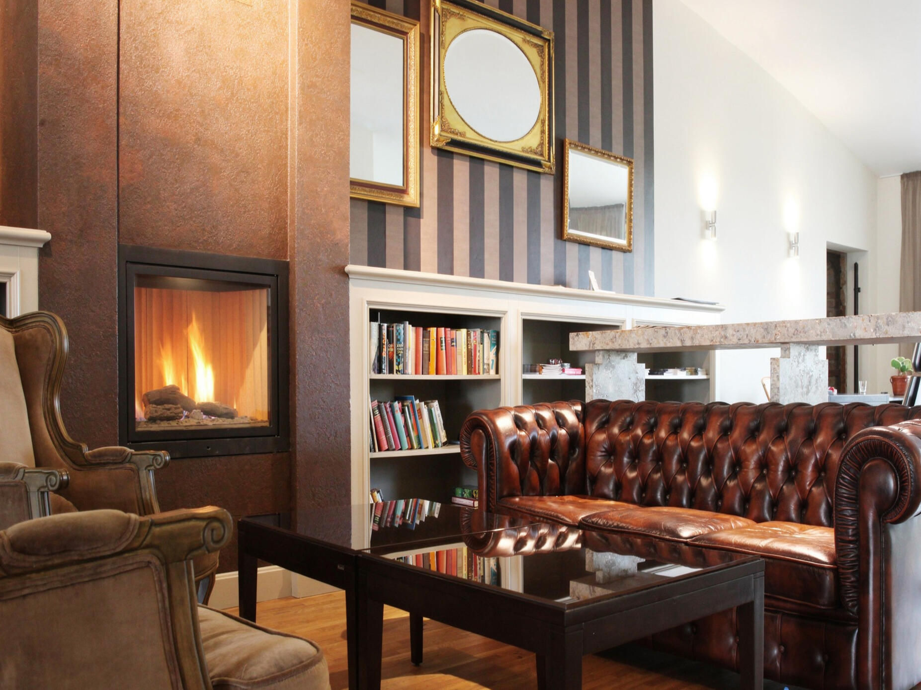 Gemütlicher Hotel-Loungebereich mit Ledersofa, Kamin und Bücherregal.