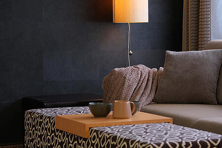 Sitzbank mit Polster und Wandlampe in warmer Beleuchtung