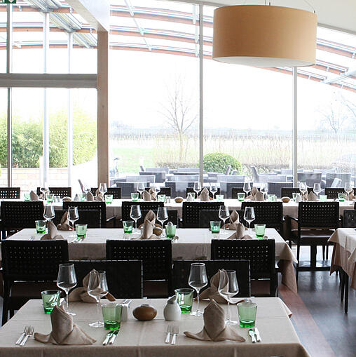 Heller Restaurantbereich mit großen Fenstern und gedeckten Tischen