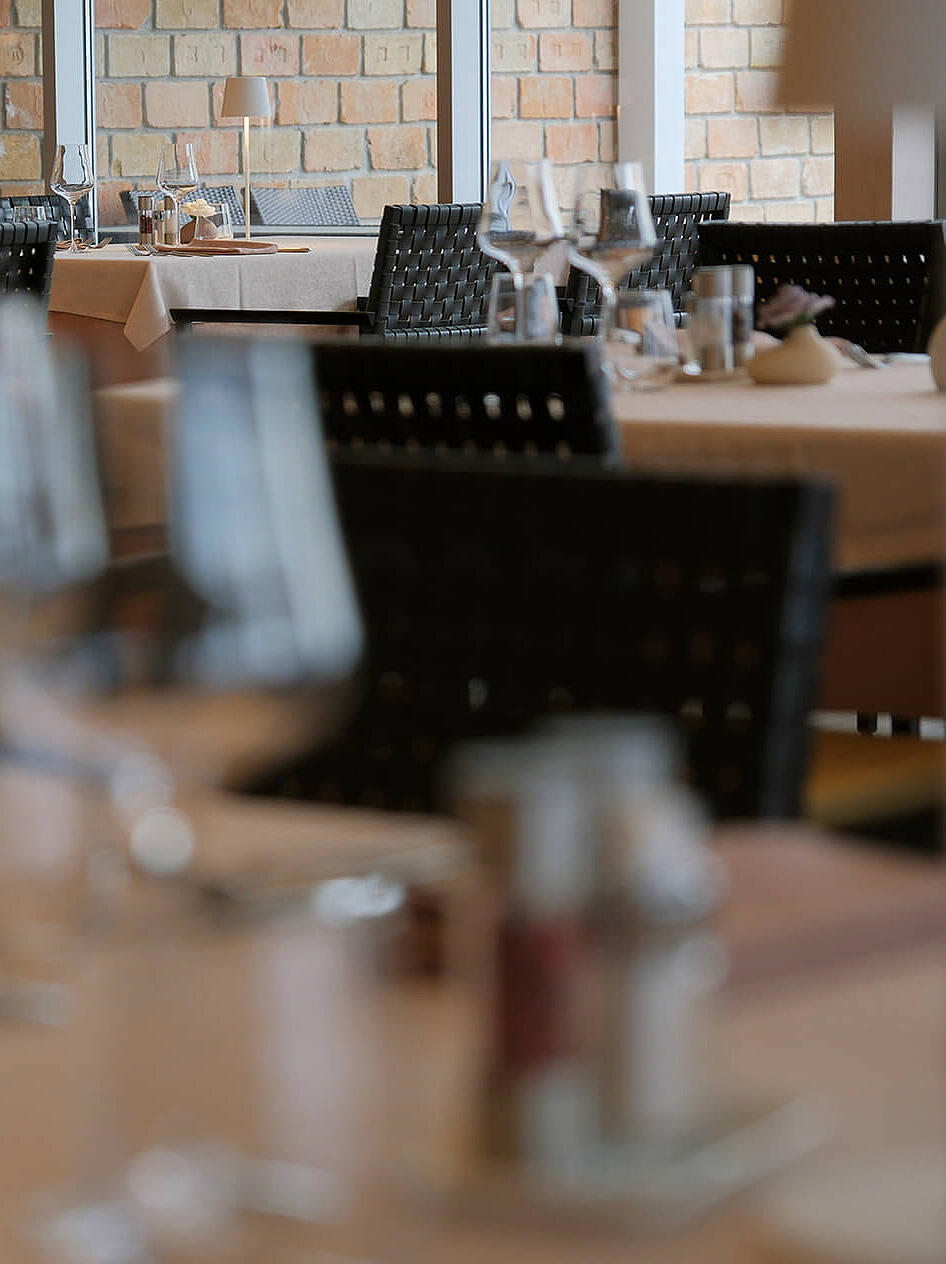 Restaurantinnenraum mit gedeckten Tischen und warmem Licht.