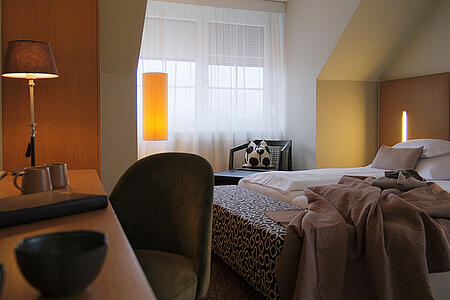 Doppelzimmer mit großem Bett, Sitzbereich und warmem Licht