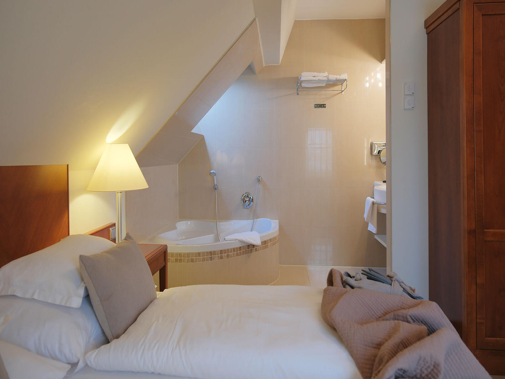 Gemütliches Doppelzimmer mit Dachschräge, großem Bett und warmer Beleuchtung