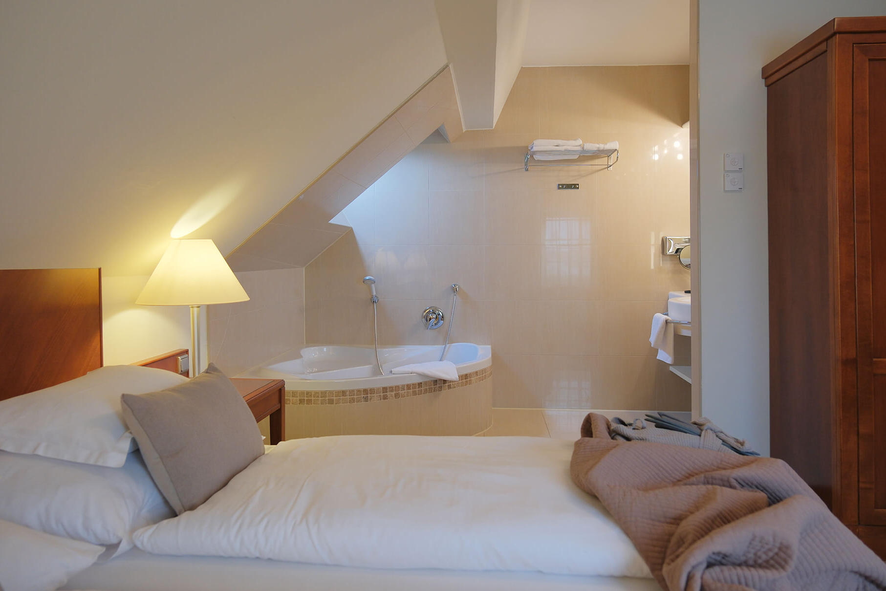 Gemütliches Doppelzimmer mit Dachschräge, großem Bett und warmer Beleuchtung