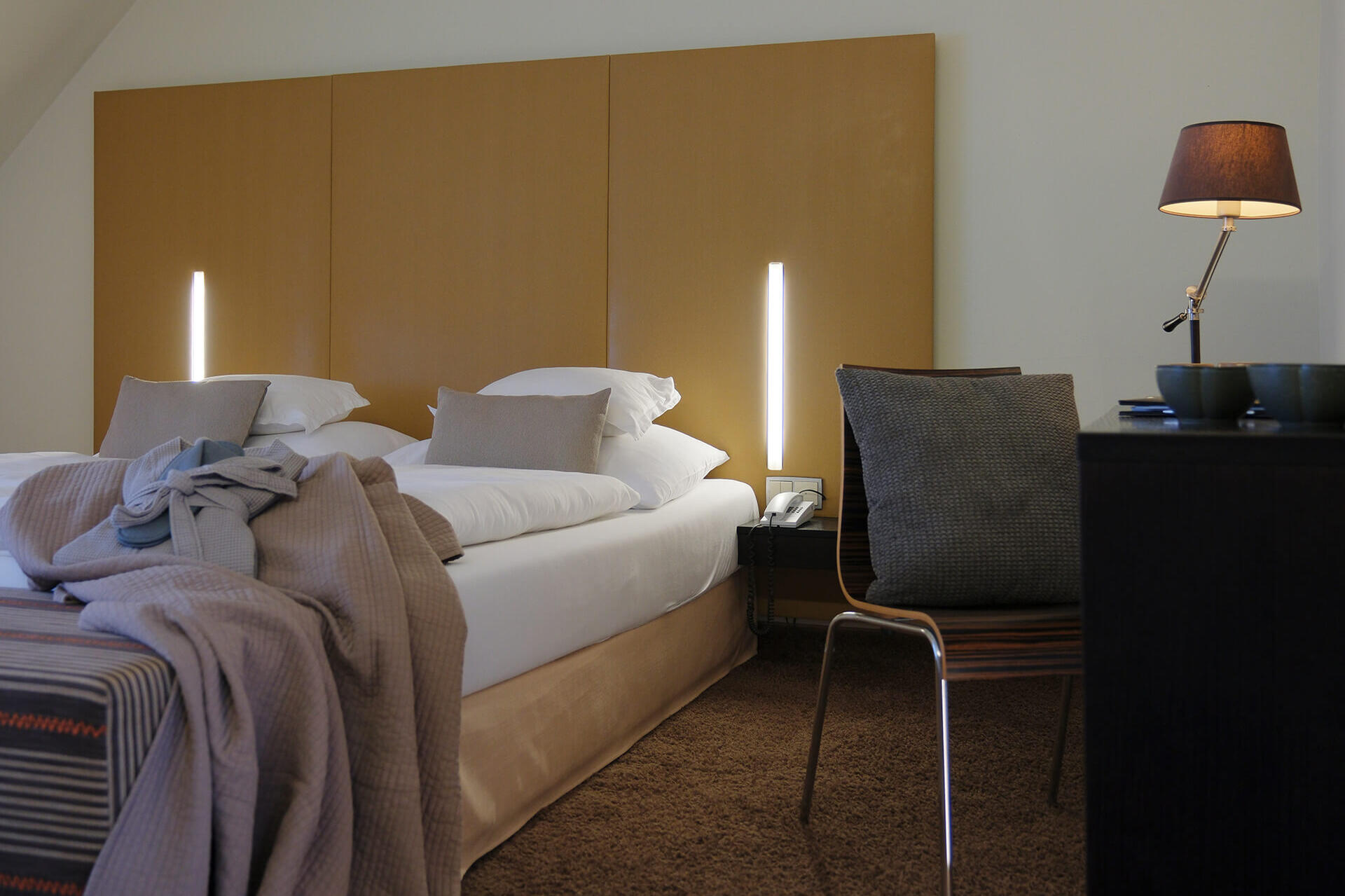 Doppelzimmer mit großem Bett, warmen Lichtakzenten und Sitzbereich