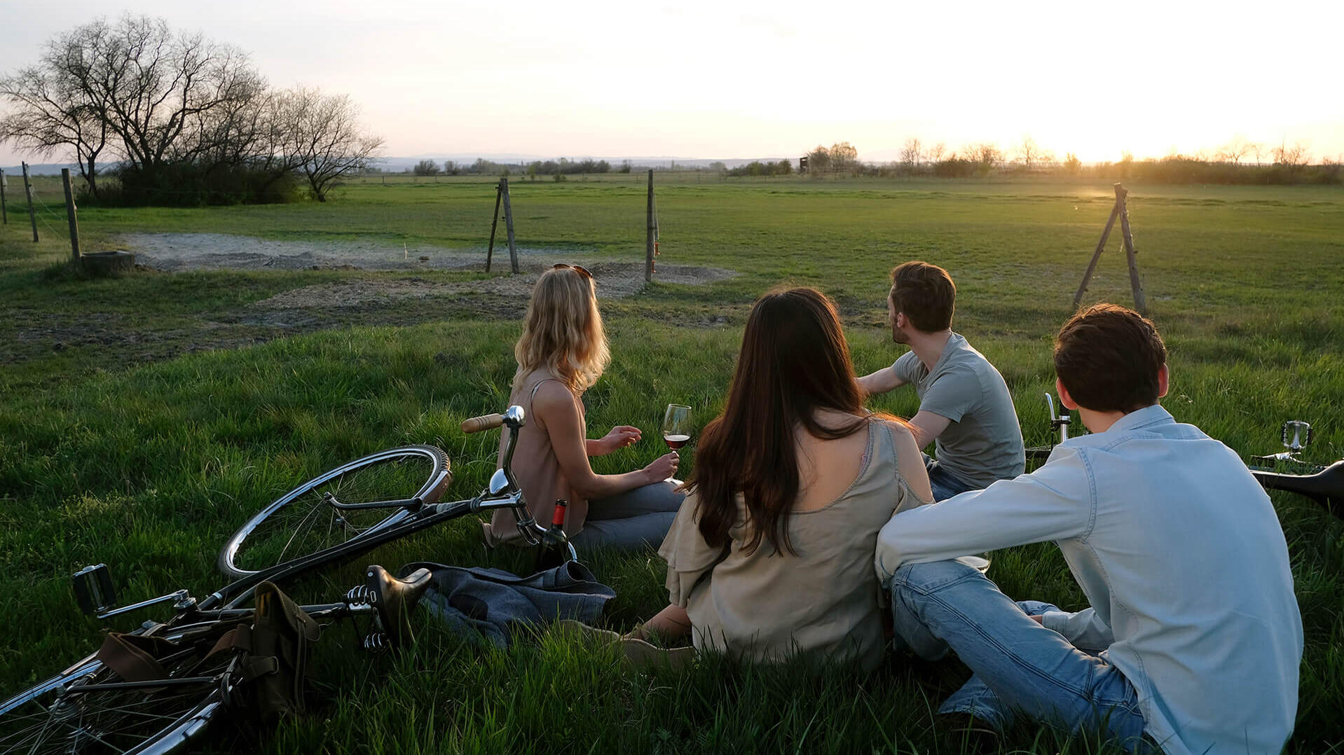 Personengruppe auf einer Wiese mit Blick Richtung Sonnenuntergang