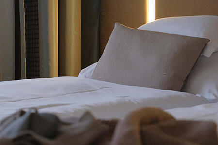 Bett mit Kissen und indirekter Beleuchtung in natürlichen Farbtönen