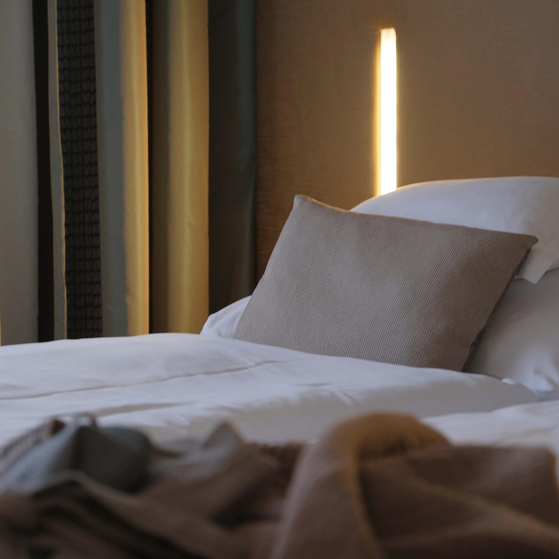 Bett mit Kissen und indirekter Beleuchtung in natürlichen Farbtönen