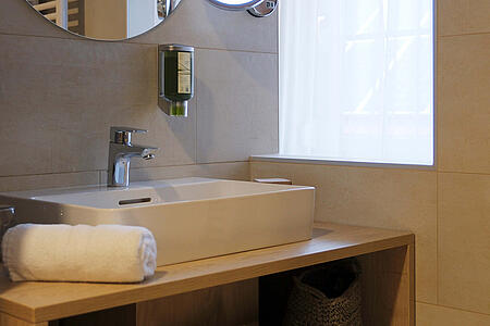 Modernes Badezimmer mit Waschbecken, Spiegel und Stauraum