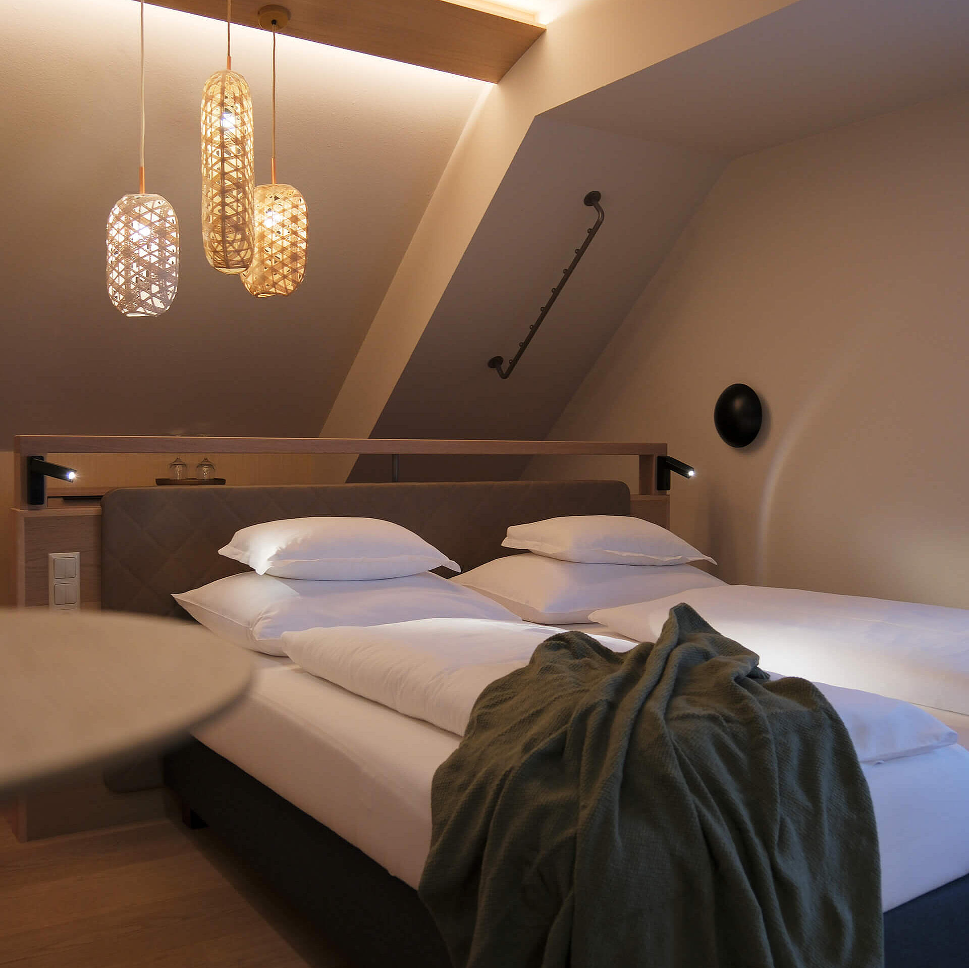 Doppelzimmer mit großem Bett, warmen Lichtakzenten und Sitzbereich