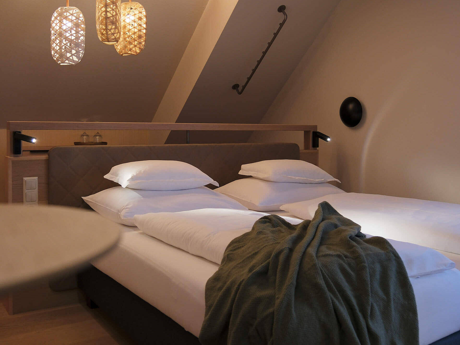 Doppelzimmer mit großem Bett, warmen Lichtakzenten und Sitzbereich