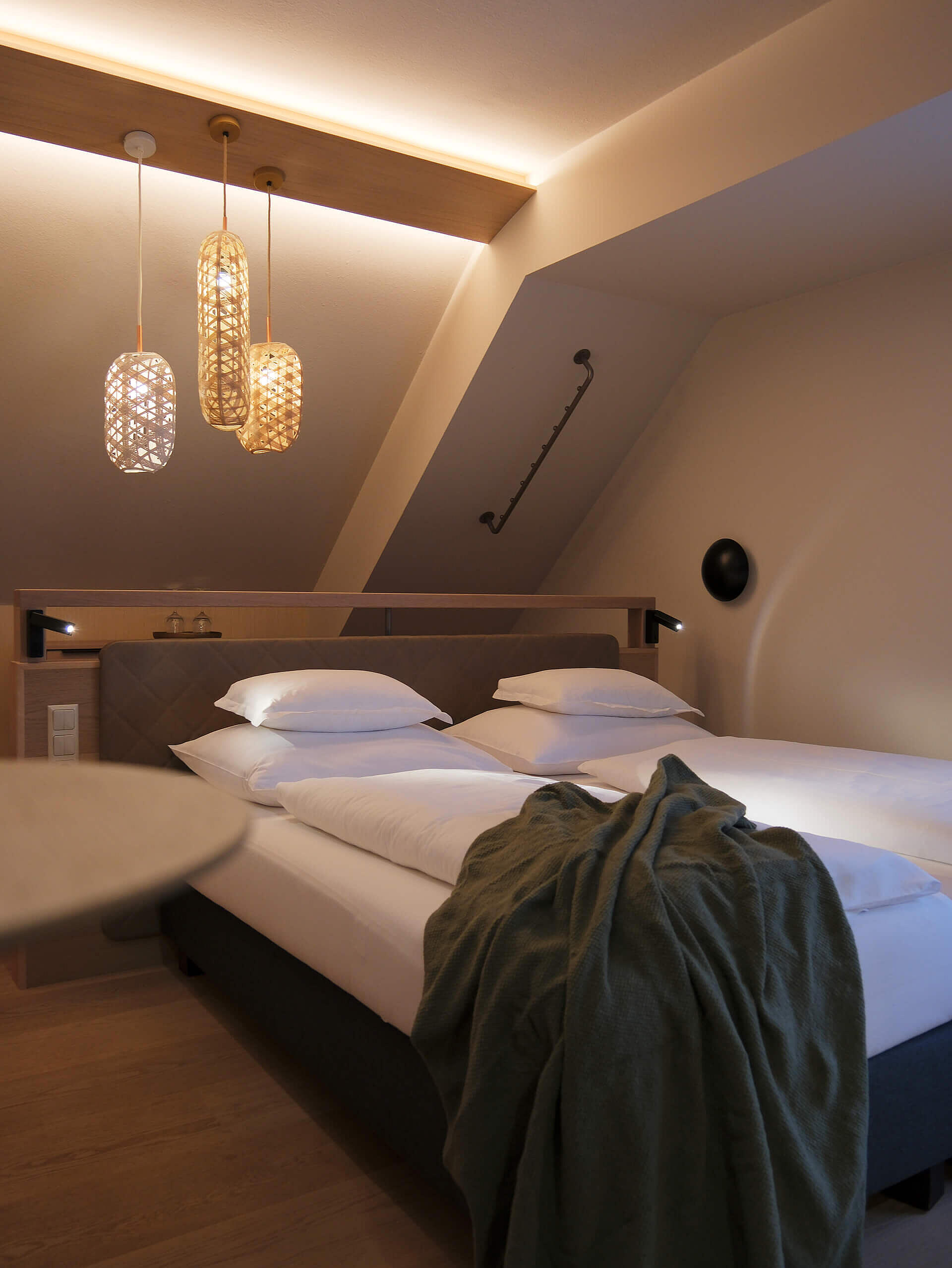 Doppelzimmer mit großem Bett, warmen Lichtakzenten und Sitzbereich