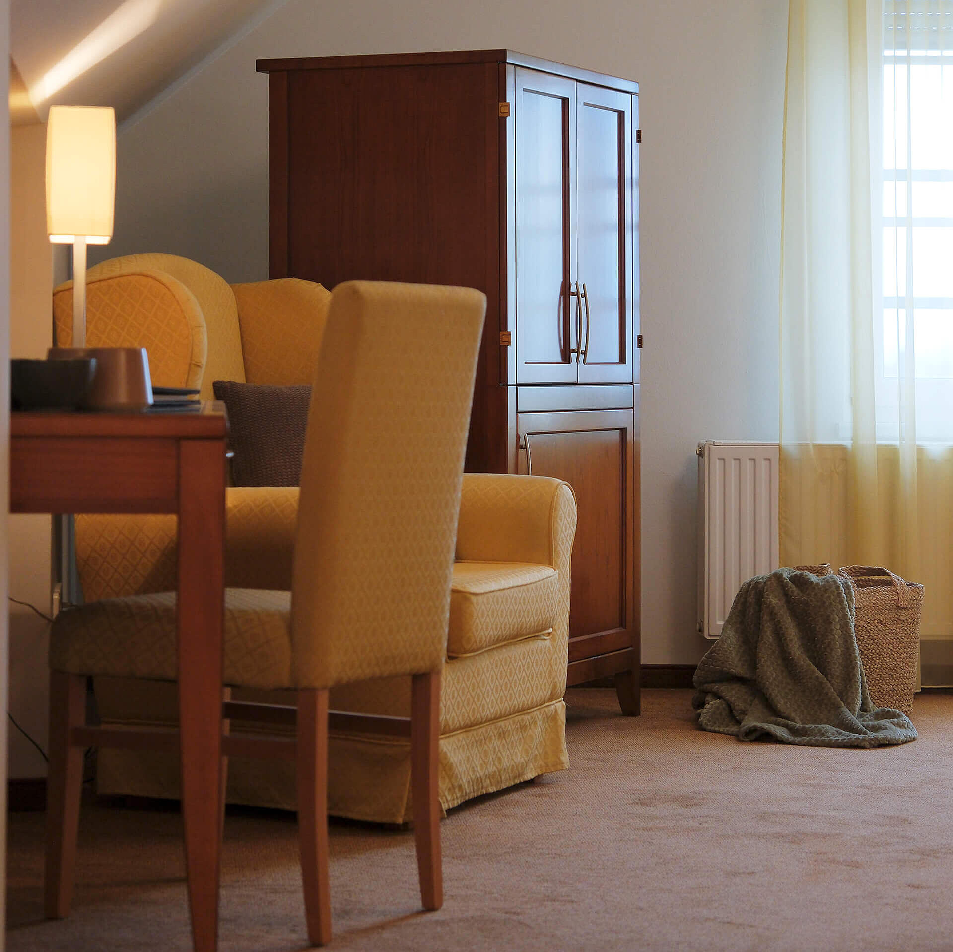 Sitzbereich mit Sessel, Tisch und Fenster im hellen Zimmer