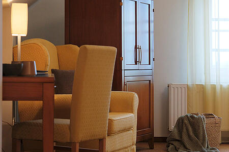 Sitzbereich mit Sessel, Tisch und Fenster im hellen Zimmer