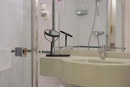 Modernes Badezimmer mit Waschbecken, Dusche und klarer Linienführung