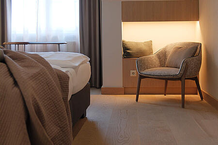 Zimmerblick mit Bett im Vordergrund und gemütlicher Sitzecke im Hintergrund