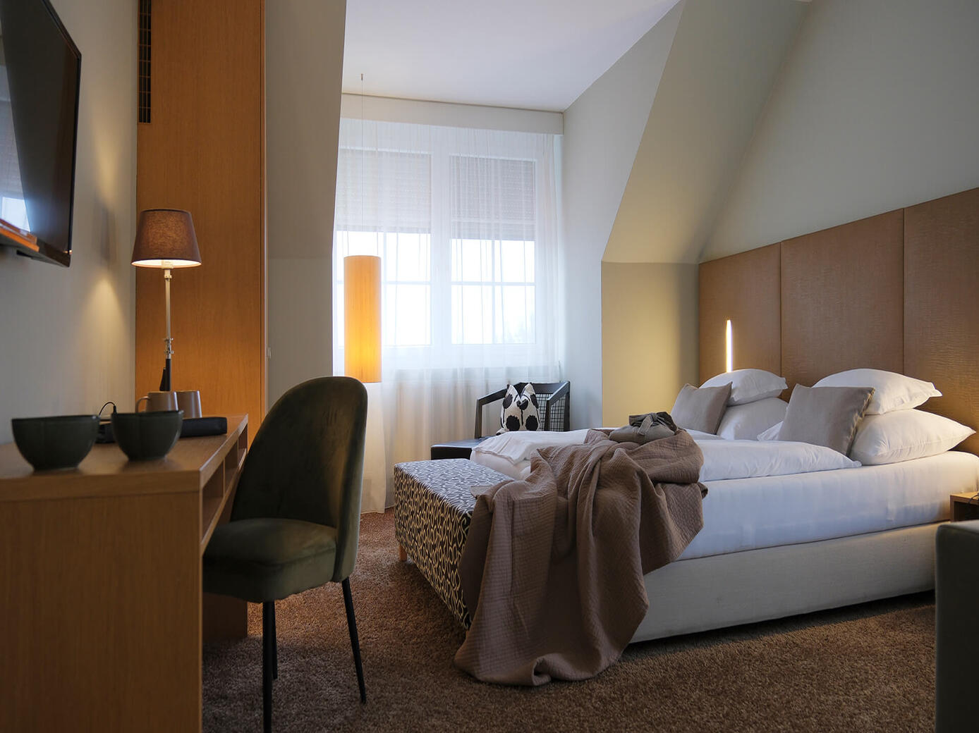 Helles Doppelzimmer mit Sitzbereich, Nachttisch und warmer Beleuchtung