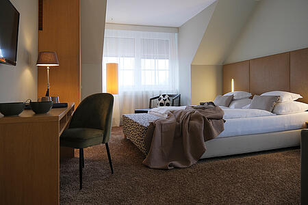 Helles Doppelzimmer mit Sitzbereich, Nachttisch und warmer Beleuchtung