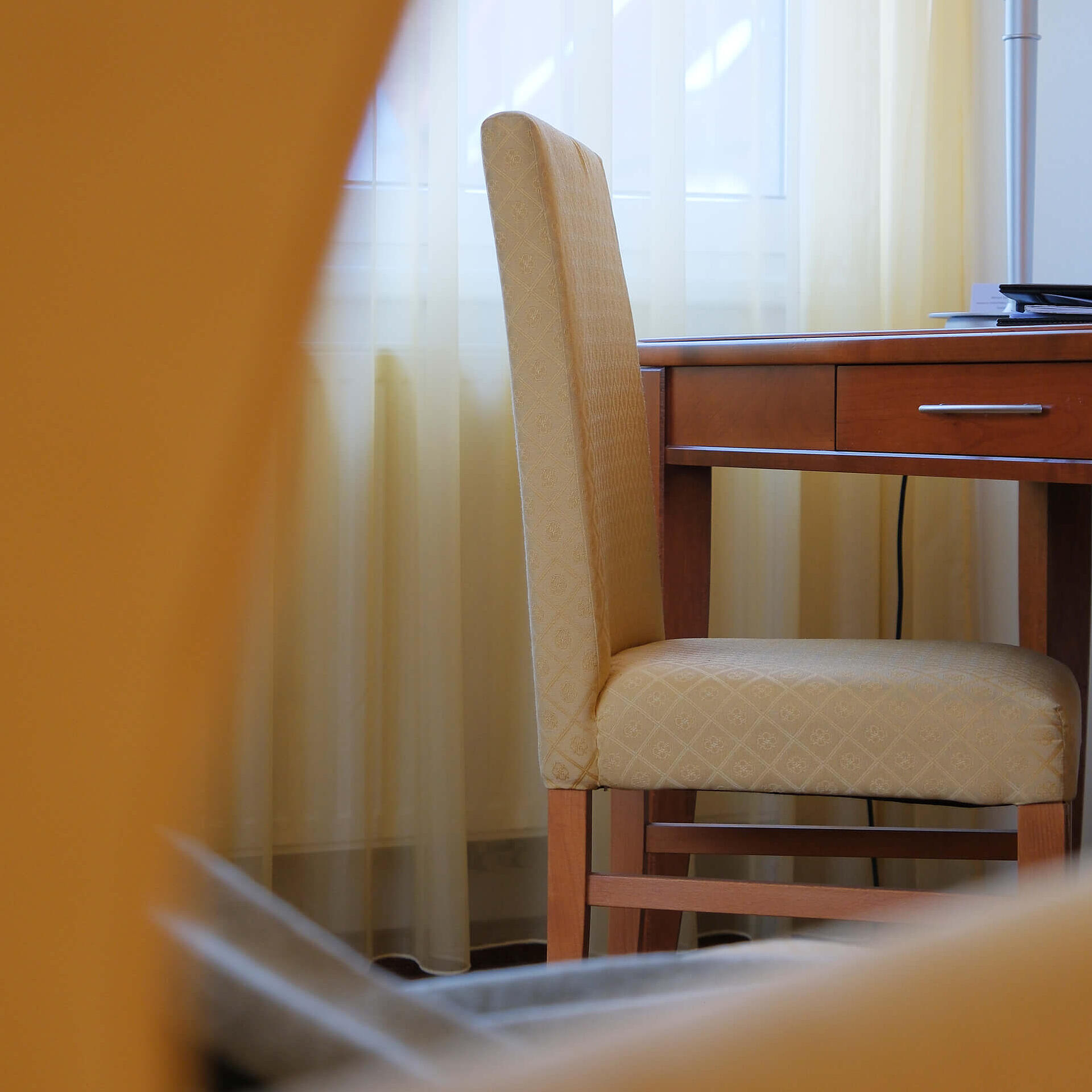 Blick durch einen Sessel auf einen Schreibtisch am Fenster