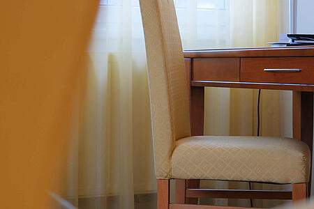 Blick durch einen Sessel auf einen Schreibtisch am Fenster