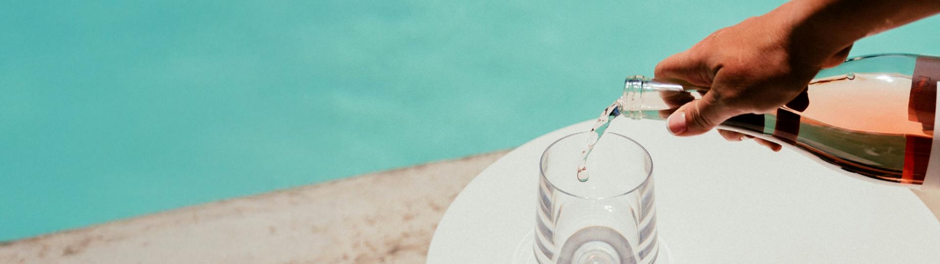 Frizzante wird in ein Glas, das am Poolrand steht, eingefüllt