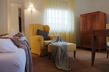 Gemütlicher Sitzbereich mit Sessel, Tisch und Schrank nahe dem Fenster