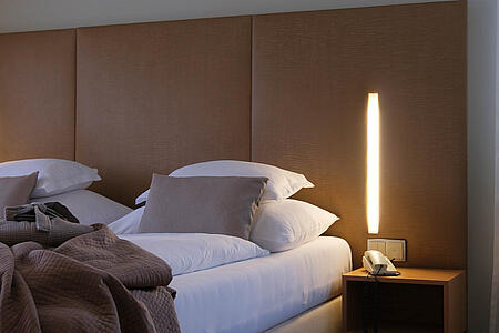 Detailansicht des Bettes mit Nachttisch und moderner Stehleuchte