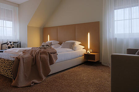 Zimmeransicht mit Bett, Schreibtisch und Fenster im Hintergrund