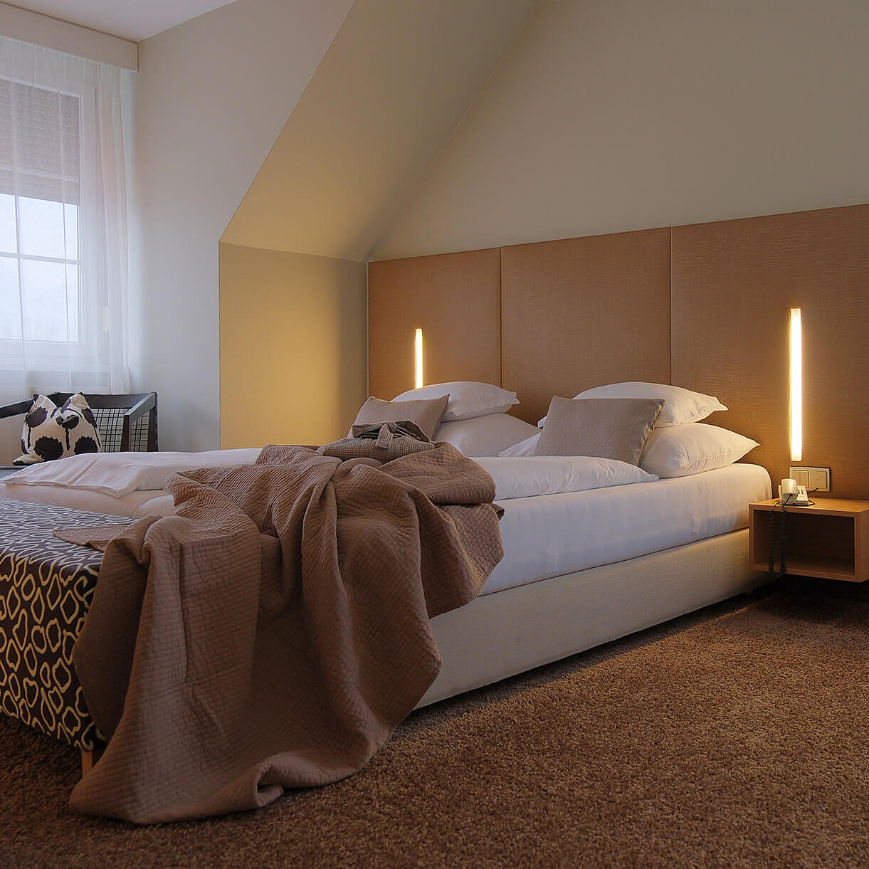 Zimmeransicht mit Bett, Schreibtisch und Fenster im Hintergrund