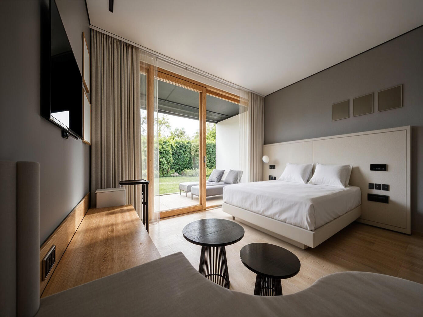 3D-Rendering eines hellen Doppelzimmer mit Holzelementen, großem Bett und Blick zur Gartenterrasse