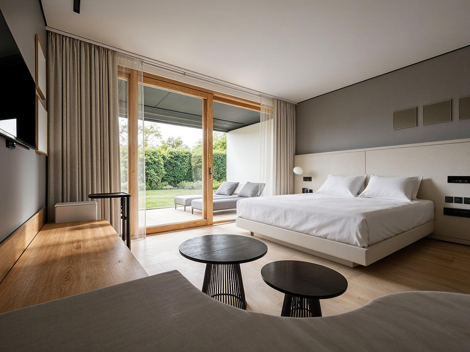 3D-Rendering eines hellen Doppelzimmer mit Holzelementen, großem Bett und Blick zur Gartenterrasse