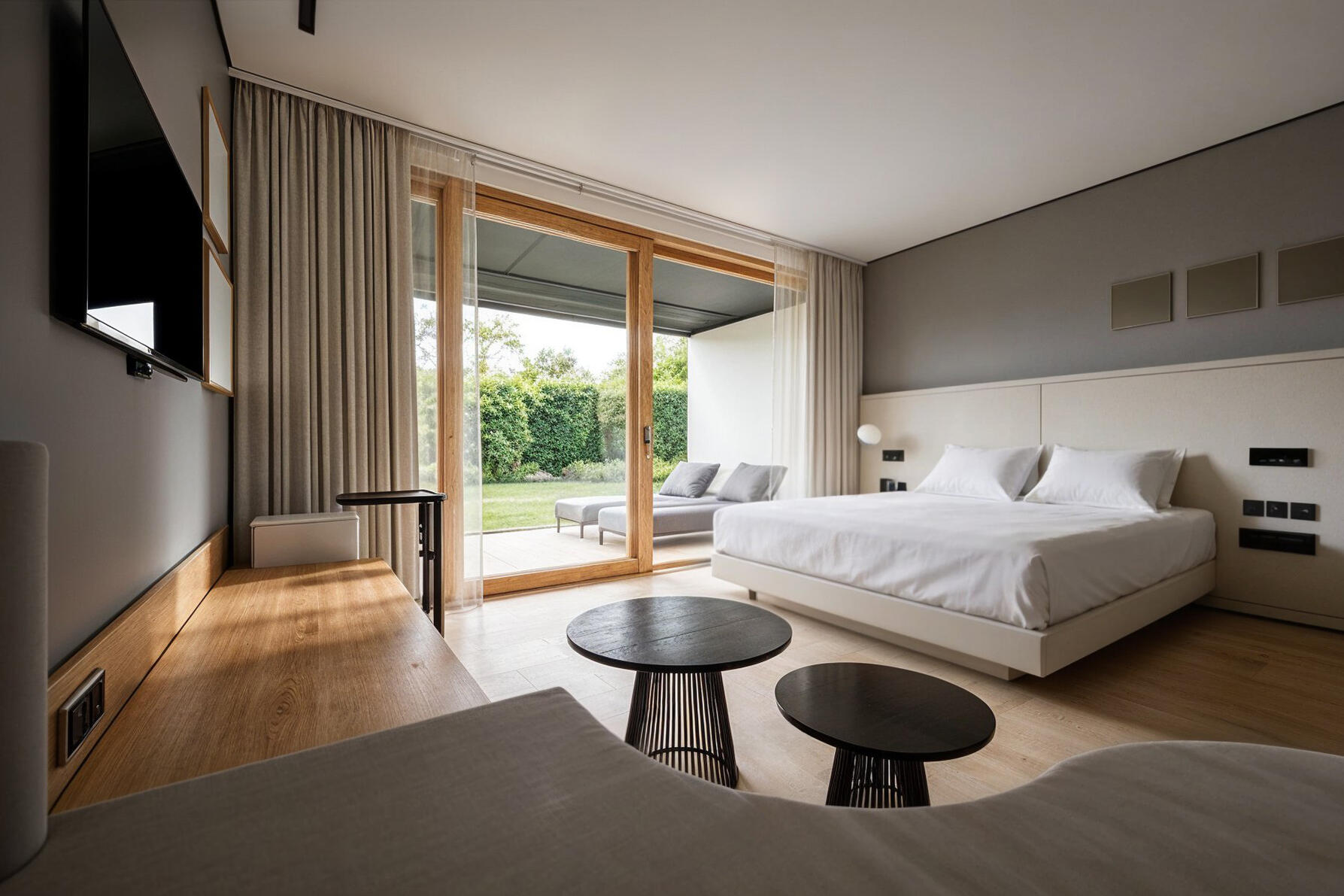 3D-Rendering eines hellen Doppelzimmer mit Holzelementen, großem Bett und Blick zur Gartenterrasse