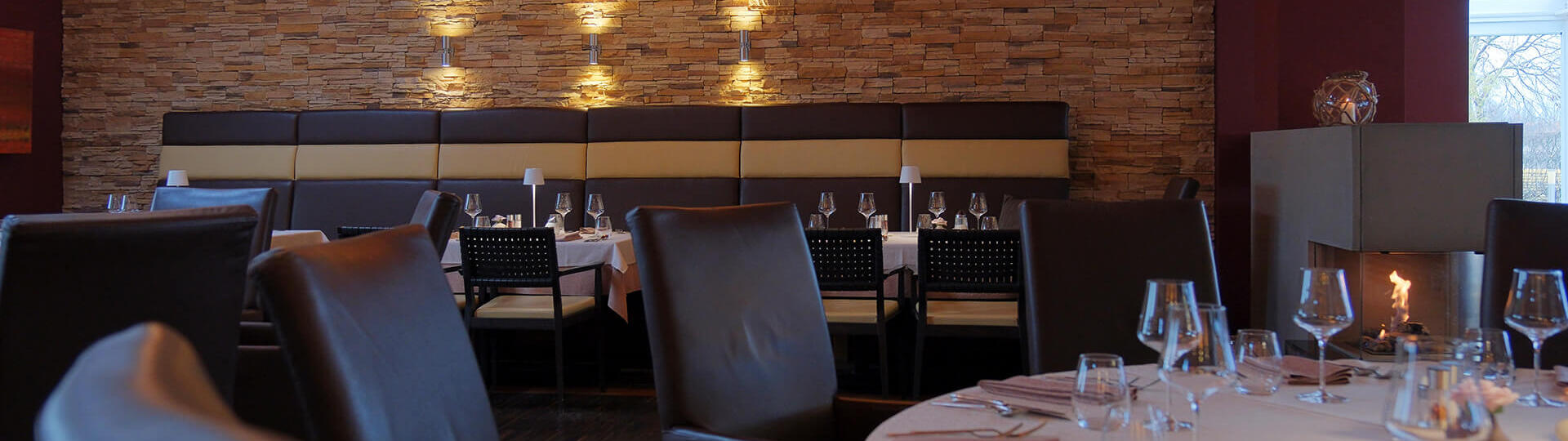 Elegantes Restaurant mit runden Tischen, Kamin und stimmungsvoller Beleuchtung.