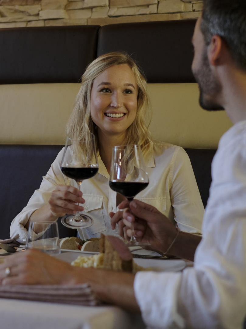 Ein Paar genießt bei Kerzenschein ein Glas Rotwein beim gemeinsamen Abendessen im stilvollen Restaurant.