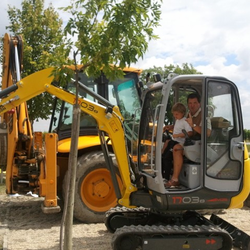 Otto Salzl mit Enkelkind sitzt am Bagger auf der Baustelle vom Hotel Nationalpark