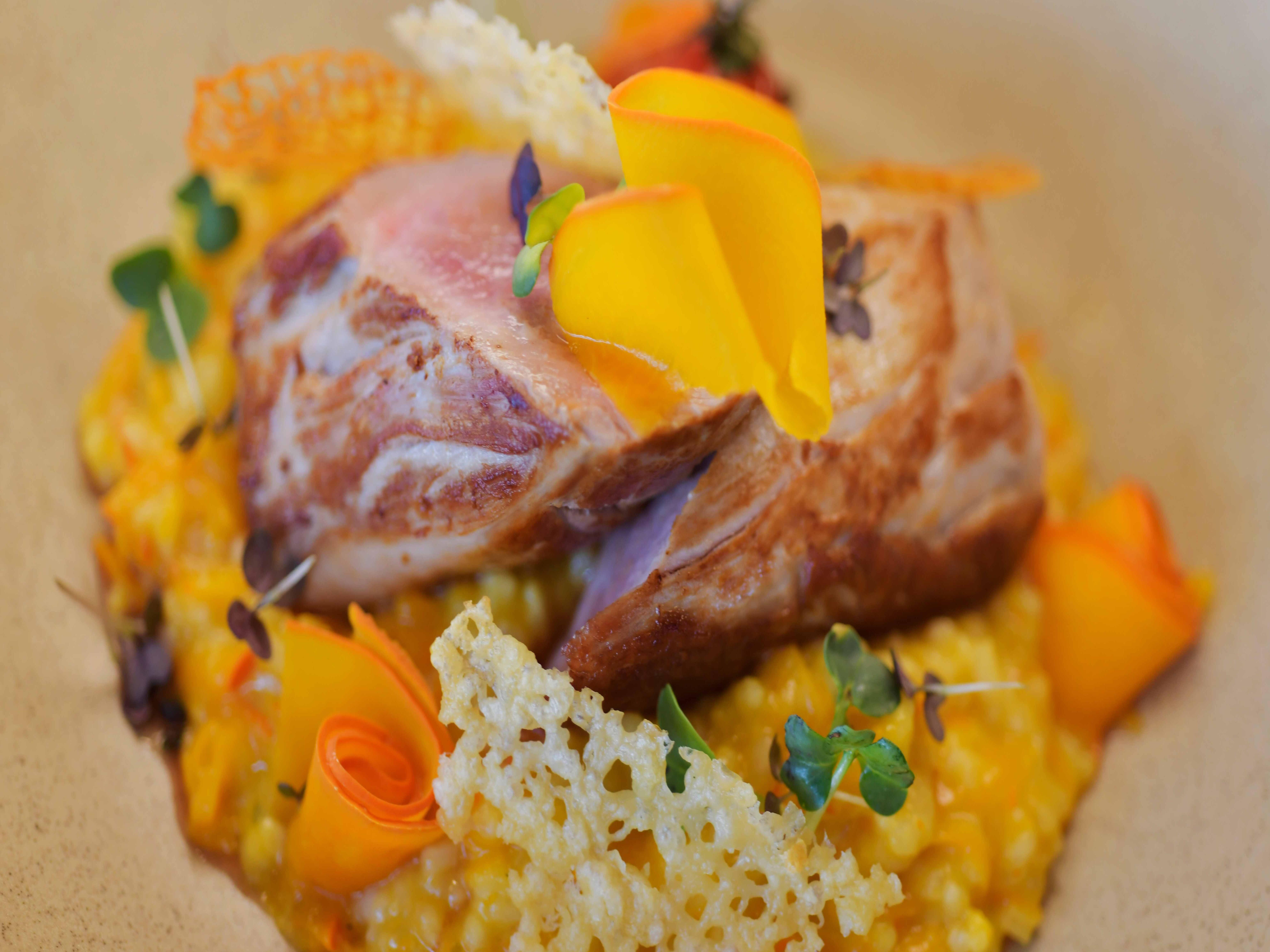 Fein angerichtetes Gericht mit Fleisch und Gemüse auf einem Teller.