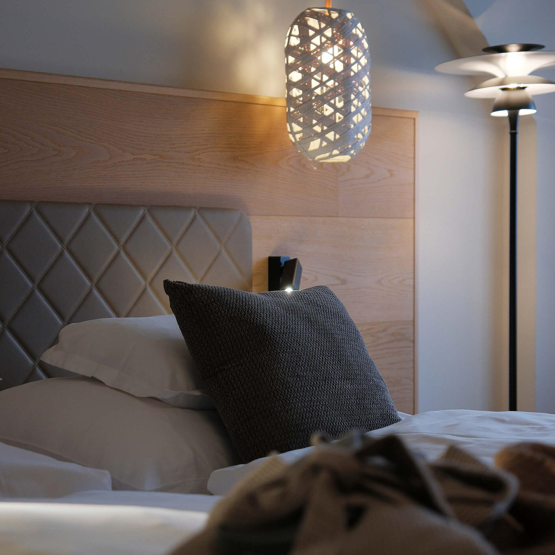 Detailansicht des Bettes mit gepolstertem Kopfteil und dekorativer Leuchte