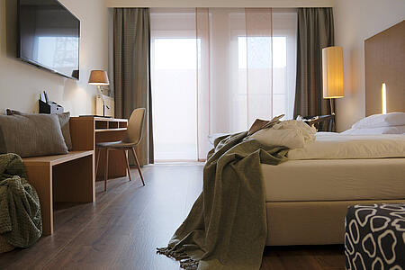 Modernes Doppelzimmer mit Bett, Stauraum und Zugang zur Gartenterrasse