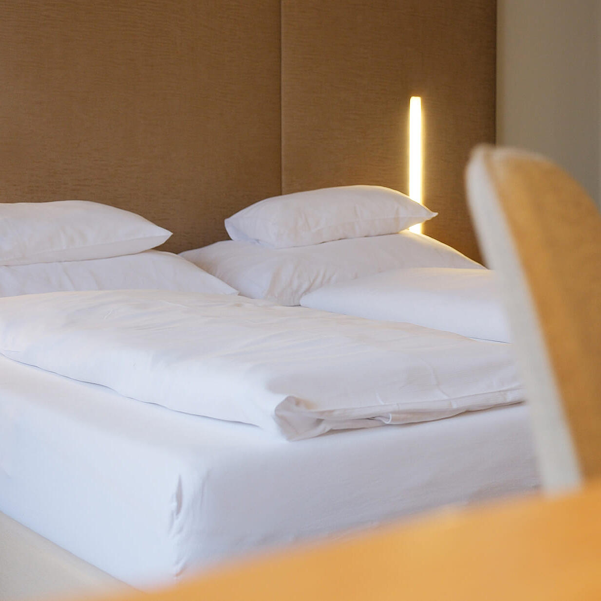 Detailansicht des Bettes mit Stuhl und harmonischer Farbgestaltung